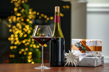 Canvas Print - Red wine and gift boxes on wooden table against blurred Christmas lights. Bokeh effect