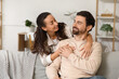 © Pixel-Shot - Happy wife hugging her husband on sofa at home