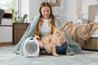 © Pixel-Shot - Young woman with plaid and Maine Coon cat sitting near electric fan heater in bedroom