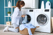 © Pixel-Shot - Young woman doing laundry in room