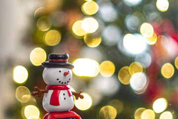 toy of a snowman with the blurred background of a Christmas tree