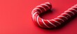 © DuangphonKPR - A festive red background with a close-up of a candy cane, showcasing its iconic striped design, evoking holiday spirit and sweetness.