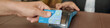 © DragonImages - Hand holding credit card while making transaction with portable card reader at table in professional setting