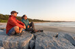 © Simon - Relaxation concept, feeling inner peace. Couple of woman and man sitting relaxed, admiring sunset, smiling.
