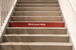 © ThamKC - Mind your step precaution message printed on step on staircase to alert people to be careful