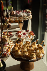 Wall Mural - A table with a variety of desserts and pastries. The desserts are arranged in glass bowls and trays