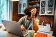© Davor - Man studying from home eating pizza while using laptop in a cozy kitchen