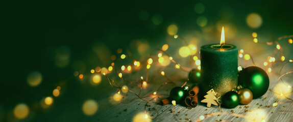 Wall Mural - burning christmas advent candle - green candle with xmas decoration and magic golden lights - christ