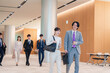 © maroke - オフィスのホールで話しながら歩くビジネスパーソン