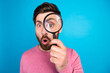 © deagreez - Curious bearded man exploring with magnifying glass against vibrant blue background, playful expression