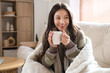 © Pixel-Shot - Young woman with warm plaid and cup of coffee at home on winter day
