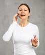 © JackF - Smiling adult woman in casual clothes talking on mobile phone in studio