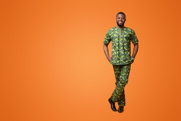 Wall Mural - Handsome black man in traditional african green clothes posing over yellow studio background