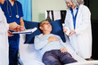 © NanSan - A female doctor examines an elderly man lying on a hospital bed, addressing chronic conditions like neurological disorders, coronary heart disease, bone disease,diabetes,disease,disease,hypertension