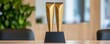 © lnwAI - Shiny golden awards trophy displayed on a wooden table with a blurred office background, symbolizing achievement and recognition in the workplace.