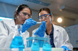 © Phimwilai - Medical laboratory Biology research development Advanced equipment Two female scientists working using test tubes blue solution Analyze biochemical samples in a medical science laboratory.