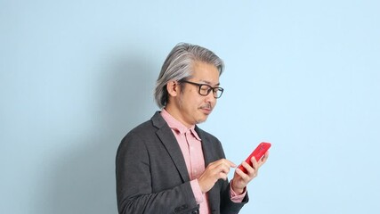 Wall Mural - The senior Asian man standing on the blue background.