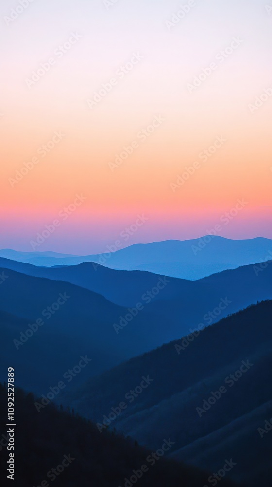 A vibrant sunset casts shades of pink and blue over the rolling mountain ranges, creating a tranquil atmosphere.