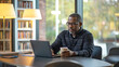© Nataliia - Focused African American man working on a laptop in a modern library, holding a coffee cup, surrounded by bookshelves and warm lighting, creating a professional and studious atmosphere