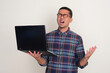 © KrishnaTedjo - A man showing expression of regret while holding a laptop