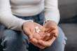 © Yura Yarema - Suicide depressed or despair concept. Close up of drug addict young woman hand holding pills, medicament on couch at home, abuse overdose. Sick pain of health, unhealthy people
