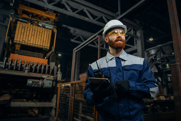 Wall Mural - Portrait of male engineer wearing safety vest and working in manufacturing factory with bricks