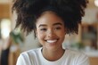 © Odin AI - A cheerful woman with a large afro hairstyle beams a radiant smile in a bright room, exuding warmth and positivity through her expressive features and relaxed demeanor.
