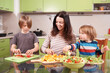 © sandsun - Happy family preparing healthy food in the kitchen, mother and children making wraps and cutting vegetables, teamwork, healthy eating, bright home atmosphere