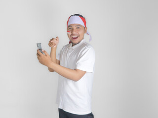 Wall Mural - Excited young Asian men celebrate Indonesian independence day on 17 August while holding mobile phone isolated over white background