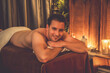 © InfiniteFlow - Caucasian man customer enjoying relaxing anti-stress spa massage and pampering with beauty skin recreation leisure in warm candle lighting ambient salon spa at luxury resort or hotel. Quiescent