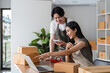 © wichayada - Young Couple Managing Online Business from Home, Checking Product Stock and Orders on Laptop in Modern Workspace