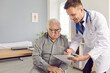 © Studio Romantic - Young friendly smiling male doctor showing test results to his senior elderly gray-haired man patient and prescribe treatment to him in medical clinic after examination. Health care concept.