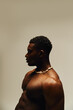 © LIGHTFIELD STUDIOS - A young, striking African American man poses topless in a creative indoor setting, exuding self assurance and charm.