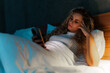 © DusanJelicic - Blonde woman looking at her phone while laying in bed.