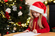 © New Africa - Little girl writing letter to Santa Claus at table indoors. Christmas celebration