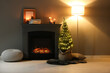 © New Africa - Small spruce tree in basket decorated with Christmas lights near fireplace indoors