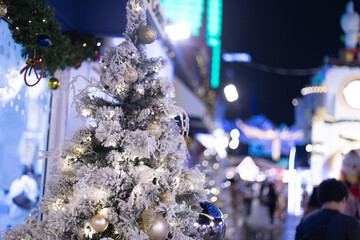 close up snowy Christmas tree with decoration ball and light bulb on festival market mall event time celebrations and Crowd people