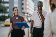 © qunica.com - A diverse group of business professionals walking with smiles in an urban setting, reflecting teamwork, collaboration, and positivity. Perfect image for promoting diversity and modern business