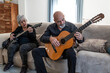 © Antonio Recena - Couple, 70 years old, playing guitar on the sofa in their living room. Woman electric, Man, acoustic