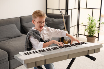 Wall Mural - Cute little boy playing modern synthesizer at home