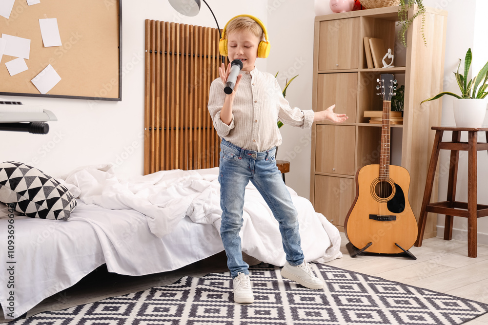 Cute little boy with headphones and microphone singing at home