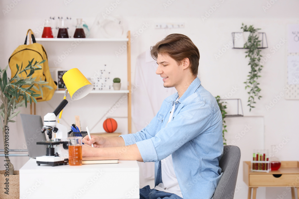 Male student with microscope on table studying at home