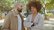 © Krakenimages.com - An interracial couple stands in a city park, appearing engaged in a serious conversation, surrounded by urban greenery and street elements.