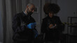 © Krakenimages.com - A man and woman, appearing as detectives, examine evidence in an indoor crime scene investigation.