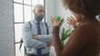 © Krakenimages.com - A bald man and an african american woman engaged in a serious conversation indoors with a modern window backdrop.