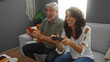 © Krakenimages.com - Middle aged couple enjoying a fun gaming session together on a couch in their cozy living room.