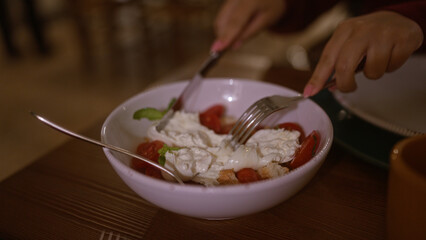 Poster - Woman dining indoors at an italian restaurant, enjoying a bowl of fresh burrata salad with tomatoes.