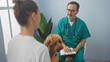 © Krakenimages.com - A veterinarian in scrubs consults with a woman holding a poodle in a clinic room interior, implying healthcare for pets.