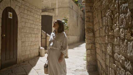 Wall Mural - Young hispanic woman strolling through the old town streets of bari, italy, basking in the warm sunlight against ancient stone walls.