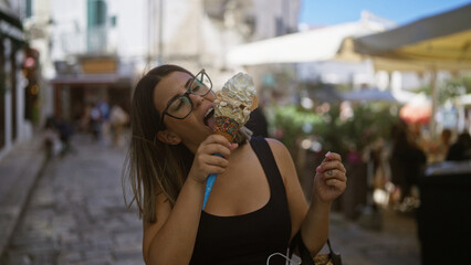 Wall Mural - A young hispanic woman enjoying a large ice cream cone on a sunny day in the charming old town streets of puglia, italy.